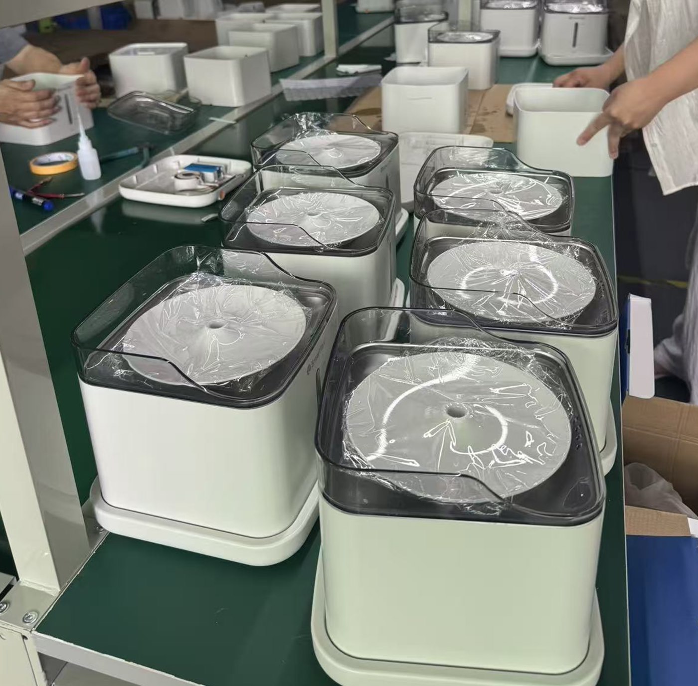 Finished smart litter boxes on a line with protective film applied over the drum opening before packing