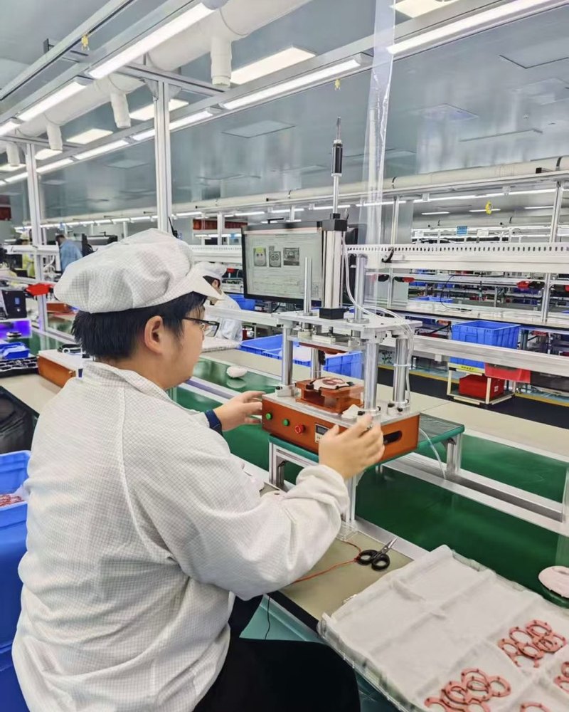 Operator assembling electronics inside a product housing at a production bench
