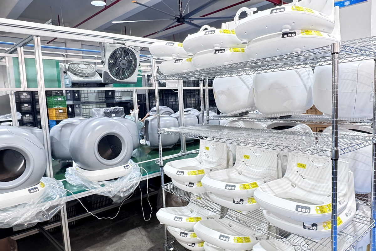 Finished smart litter box units on multi-tier wire shelving in a production area
