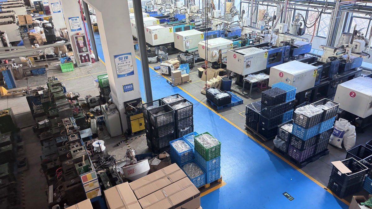 Injection moulding workshop with numbered moulding machines in line and work-in-progress crates along the aisle